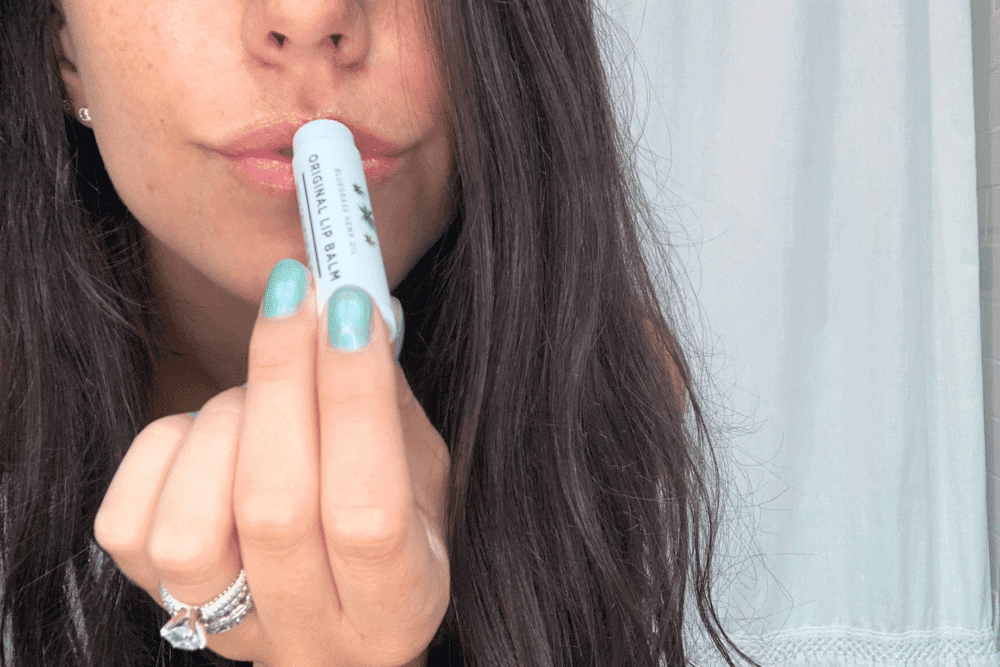 A lady applying Genesis CBD lip balm to her lips. Her lips are smooth and kissable.