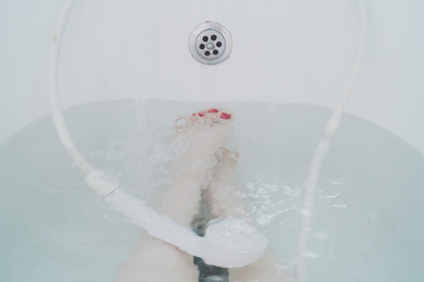 Woman's feet submerged in a bathtub filled with CBD bath soak, offering scents and relaxation.