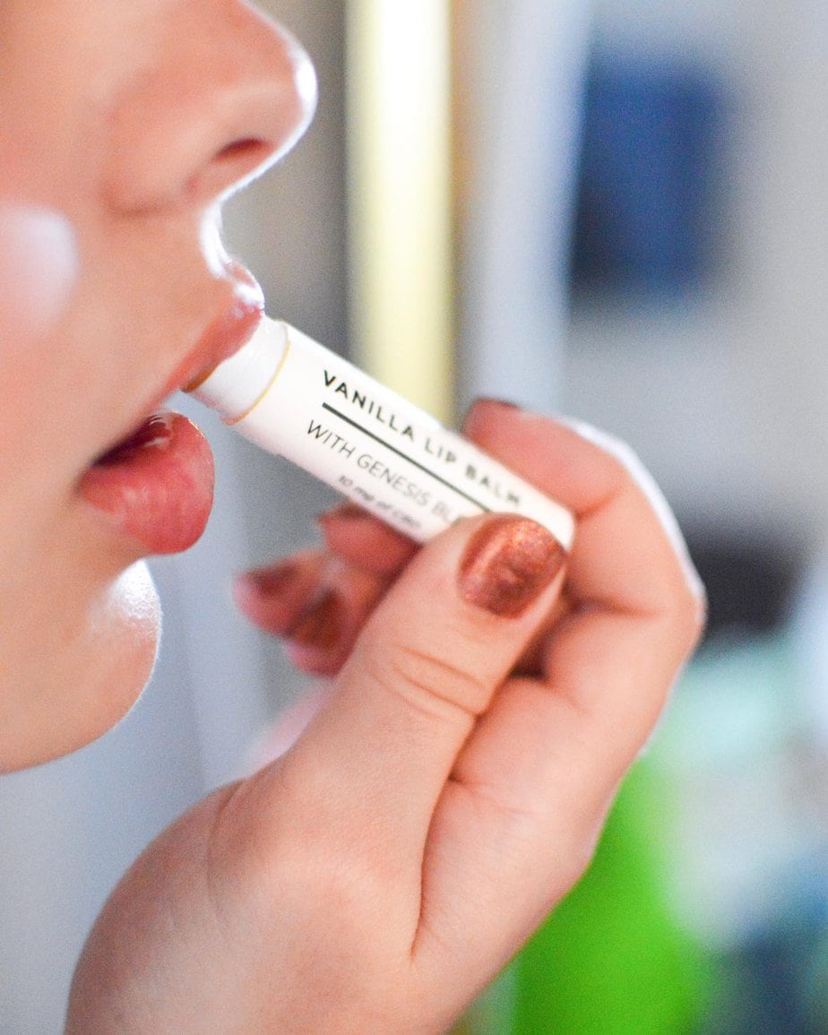 Image of a woman gracefully applying Genesis Blend CBD lip balm to her lips.