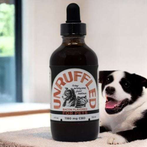 Unruffled CBD for pets 4 oz Bacon flavored bottle with a Black and white pup in the background 10mg/ml 1180 mg per bottle