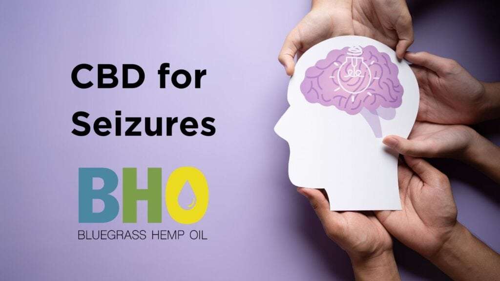 A close-up photo of hands holding a papercut depicting a human head with the words "CBD for seizures"written on it.