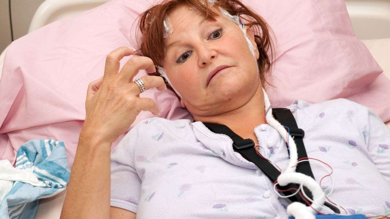 A person having a tonic-clonic seizure in a bed.