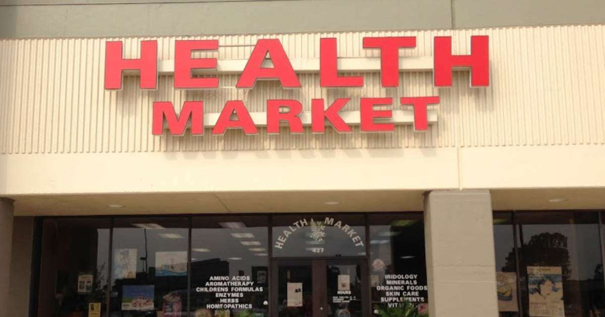 Exterior view of The Woodlands Health Food Market in The Woodlands, TX, showcasing a bright and welcoming storefront with signage displaying Genesis Blend CBD Gummies, CBD Oil for Sleep and Pain Relief.